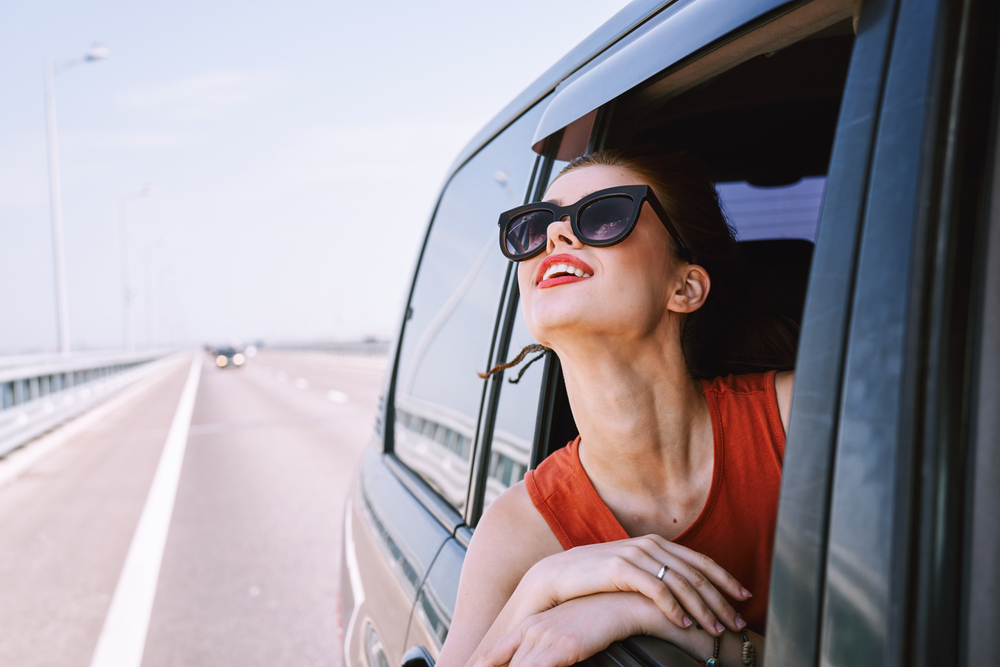 a woman is driving in a car on the road
